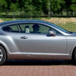 Szary samochód Bentley Continental GT w ruchu, widok z boku na tle zieleni.