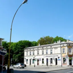 Budynek biurowy z szyldem 'ubezpieczenia' w słoneczny dzień, widok z ulicy z drzewami w tle.