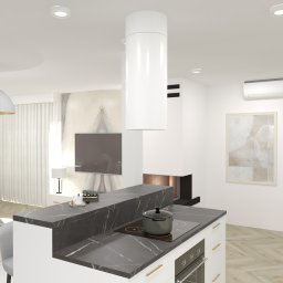 BOHO STUDIO - Wizualizacja nowoczesnej kuchni z wyspą, czarny marmurowy blat, białe szafki z poziomymi złotymi uchwytami, płyta indukcyjna z garnkiem, w tle salon z telewizorem i kominkiem.
