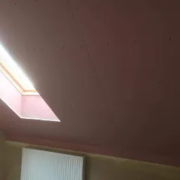 Poddasze w Tarnowie z zamontowaną płytą kartonowo-gipsową na skosach i suficie, widoczne łączenia płyt oraz okno dachowe wpuszczające jasne światło, na ścianie zamontowany biały grzejnik.