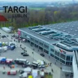 Panorama Targów Lublin z lotu ptaka, widoczny budynek hali wystawienniczej z parkingiem pełnym samochodów i zielenią w tle.