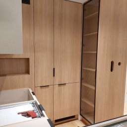 Zbigniew Czerech - Jasna, drewniana zabudowa kuchenna z szafkami cargo i szufladami w trakcie montażu. Widoczne elementy montażowe i narzędzia.