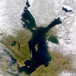 Zdjęcie satelitarne Morza Bałtyckiego z widocznymi obszarami lodu na północy, otoczonego lądem z widocznymi obszarami zieleni i chmurami.