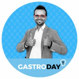 Mężczyzna w czerwonych okularach i szarym garniturze, uśmiechnięty, z uniesionymi kciukami na tle okręgu z motywem kucharza i napisem GASTRODAY.
