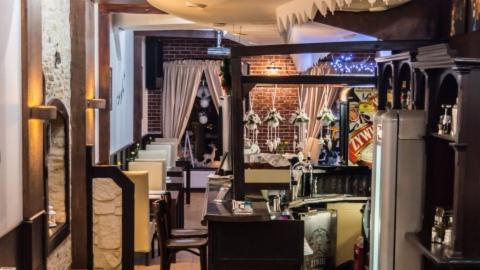 Wnętrze restauracji z elementami wystroju świątecznego, widoczne stoły, krzesła, dekoracje, bar i fragment ściany z cegły