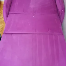 Fioletowa rozkładana kanapa po czyszczeniu, widoczne jaśniejsze ślady po ekstrakcji brudu na powierzchni tapicerki.