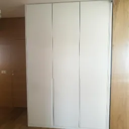 Szafa z drzwiami otwieranymi wykonana z MDF lakierowanego w półmacie. Uchwyty frezowane w pionie.