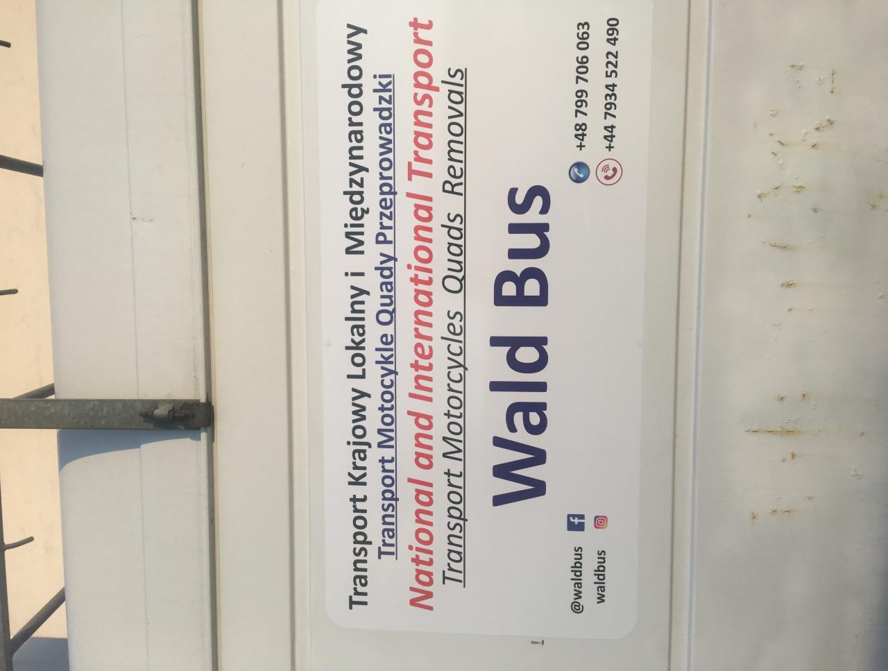 Reklama firmy transportowej Wald Bus na pojeździe, oferującej transport krajowy, międzynarodowy, motocykli, quadów i przeprowadzek. Widoczne dane kontaktowe i media społecznościowe.