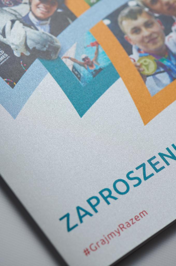 Fragment zaproszenia z motywem sportowym, zdjęcia sportowców w kolorowych ramkach, napis 'ZAPROSZENI' i hashtag '#GrajmyRazem' na srebrzystym tle.