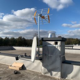 Satelis Marcin Maniecki - Antena Yagi-Uda i satelitarna zamontowane na kominie na dachu budynku, widok w słoneczny dzień. Widoczne narzędzia i akcesoria instalacyjne.