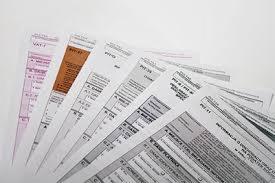 Stos dokumentów podatkowych VAT-7 i PIT-11 ułożonych wachlarzowo na białym tle, z widocznymi nagłówkami i tabelami.