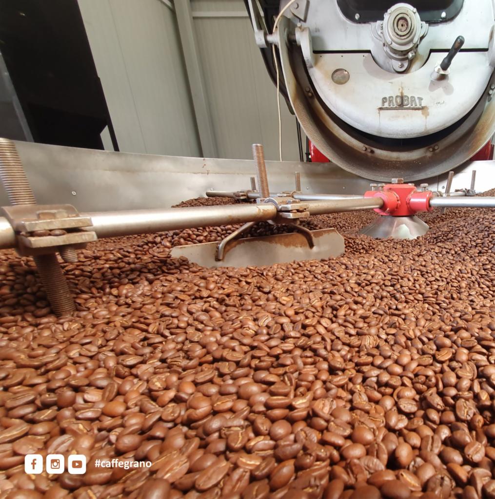 Ziarna kawy wewnątrz przemysłowego pieca do palenia kawy marki Probat z widocznym mieszadłem.