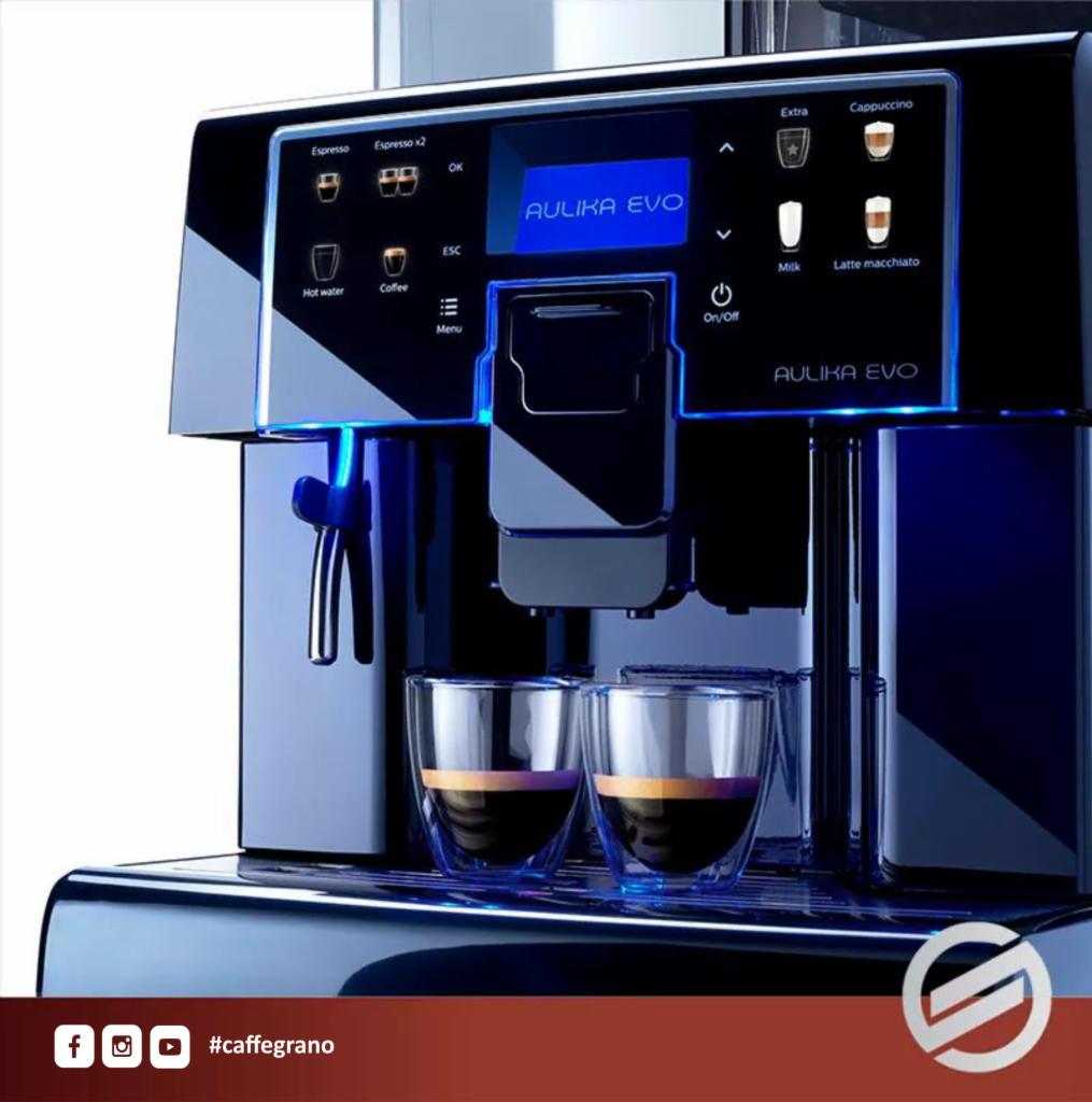 Profesjonalny ekspres do kawy Aulika Evo w kolorze czarnym, podświetlony na niebiesko, z dwiema szklankami espresso na tacce, gotowy do użycia.