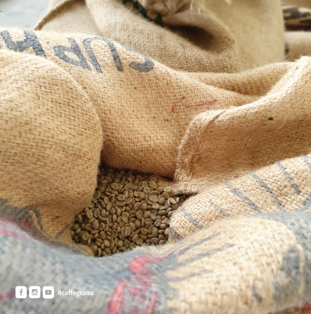 Surowe ziarna kawy w jutowym worku z nadrukiem, widok z góry.