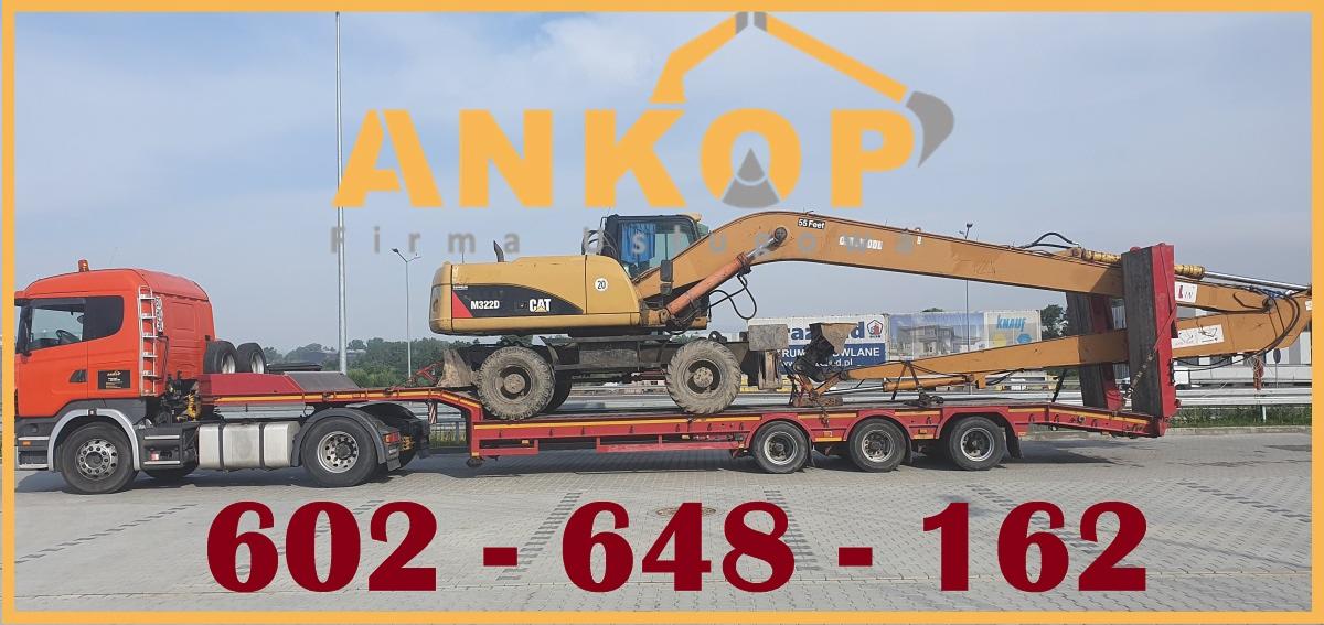 Pomarańczowy ciągnik siodłowy z naczepą niskopodwoziową przewożący żółtą koparkę kołową CAT M322D, widoczne numery kontaktowe na zdjęciu.