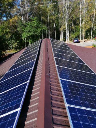 Instalacja paneli słonecznych na dachu domu w Jaworzu, widok z góry, z brązowym dachem i drzewami w tle.