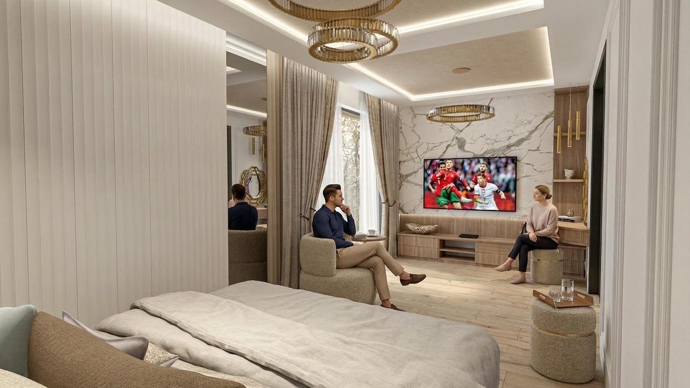 Elegancka sypialnia z marmurową ścianą, telewizorem i dwiema osobami siedzącymi w fotelach. Luksusowe oświetlenie i stonowana kolorystyka tworzą przytulną atmosferę.
