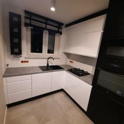 P.P.H.U WISAGE Sławomir Wierzbicki - Nowoczesna kuchnia w bieli i czerni z szarym blatem, widok na zlew, płytę gazową i piekarnik Electrolux.