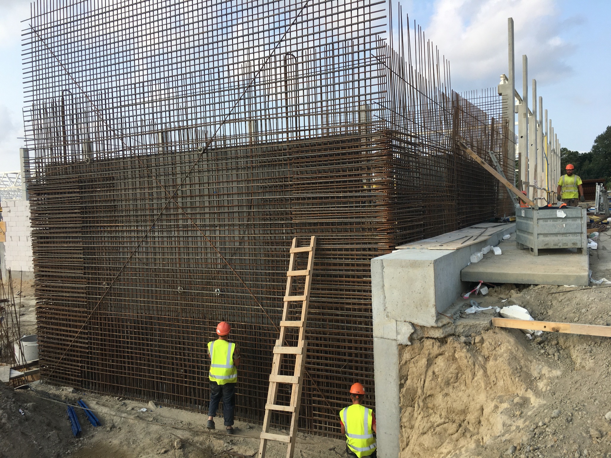 Siatka zbrojeniowa przygotowywana pod betonowanie w Szczecinie, widoczni pracownicy w kaskach i kamizelkach odblaskowych, drabina oparta o zbrojenie.