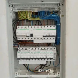 Otwarta skrzynka elektryczna z zainstalowanymi bezpiecznikami Schneider Electric, okablowaniem oznaczonym do poszczeg&oacute;lnych pomieszczeń (WC, ŁAZ, ZAHRA, ZMY, LOD, KUCH, G.SUF, G.TV, SALON, POK...