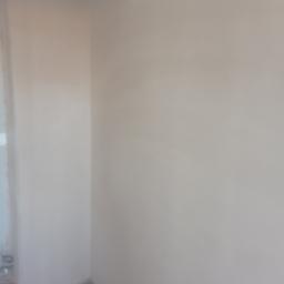 krzysztof gawor - Świeżo wykończony róg pokoju z gładkimi, jasnymi ścianami i widocznymi śladami prac wykończeniowych na podłodze.