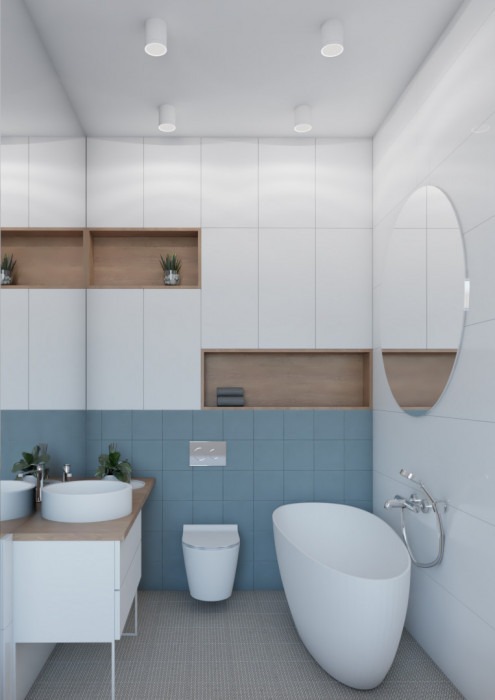Minimalistyczna aranżacja łazienki w Gdańsku z owalną wanną wolnostojącą, umywalką nablatową na drewnianym blacie, błękitnymi płytkami ściennymi i białymi szafkami, uzupełniona o rośliny w doniczkach.