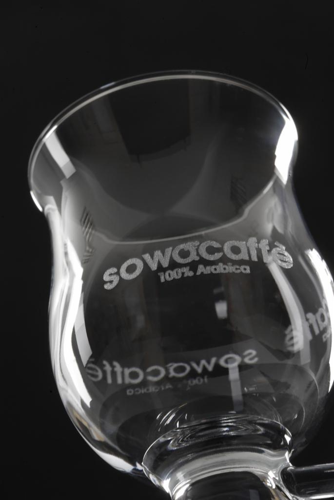 Szklany zaparzacz do kawy Sowacaffe 100% Arabica na czarnym tle, widok z dołu, podkreślający transparentność szkła i logo.