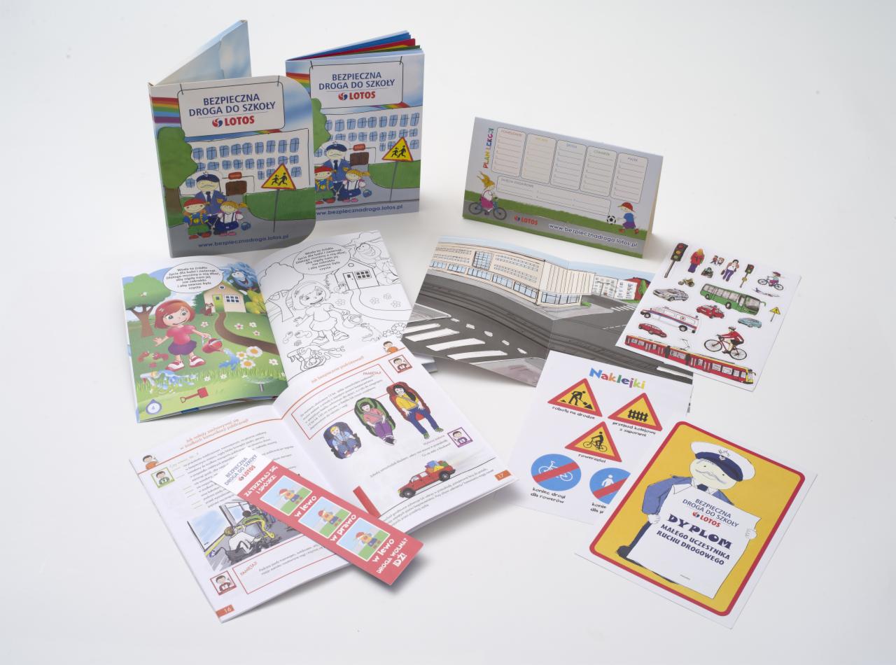 Zestaw edukacyjny dla dzieci dotyczący bezpieczeństwa na drodze, zawierający książeczki, plan lekcji, naklejki i dyplom, wszystko z logo LOTOS, rozłożone na białym tle.