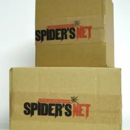 Dwa kartonowe pudełka ułożone jeden na drugim, owinięte papierową taśmą z nadrukowanym logo 'Spider's Net' w kolorach czarnym i czerwonym z motywem pajęczyny.