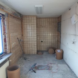 Drapinski Piotr Drapinski Usługi Ogólnobudowlane - Wnętrze w trakcie demontażu płytek, widoczna kuweta, młot udarowy i pozostałości po kleju na podłodze.