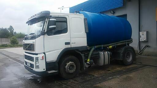 Biała ciężarówka Volvo z niebieską cysterną na podwoziu, zaparkowana na betonowym placu, widoczne węże i osprzęt.