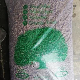 Worek z pelletem drzewnym z nadrukowanym zielonym drzewem, widoczne napisy w językach obcych.