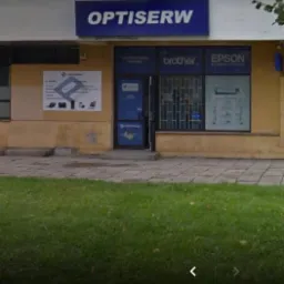 Fasada budynku firmy Optiserw z szyldem, logo i informacjami o partnerstwie z Brother i Epson, prezentująca usługi związane z komputerami i urządzeniami biurowymi.