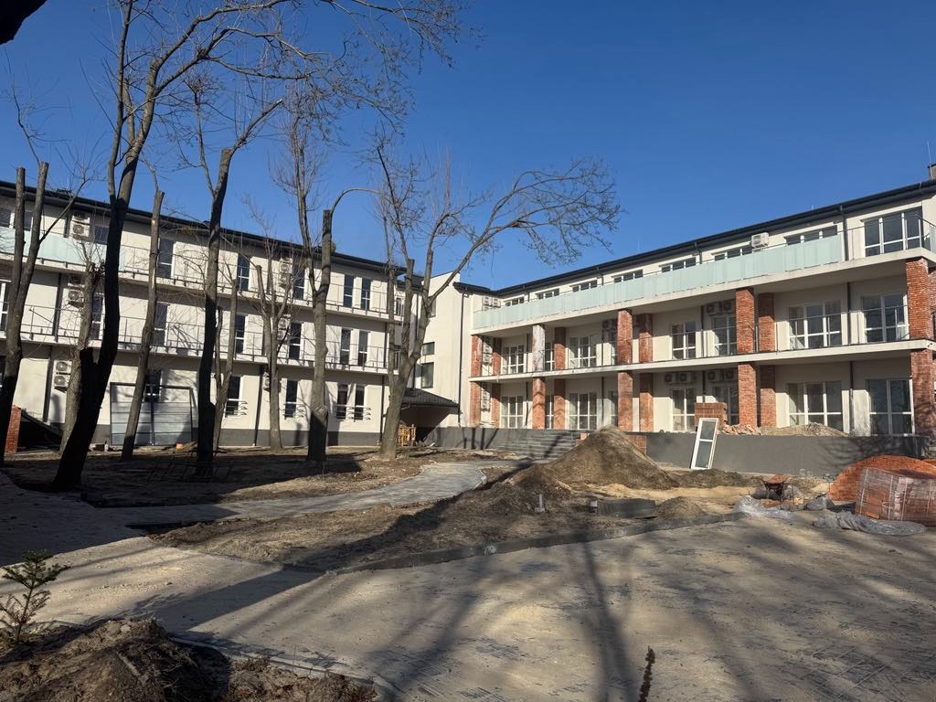 Wielopiętrowy budynek mieszkalny w trakcie wykończenia; widoczne rusztowania, cegły i piasek.