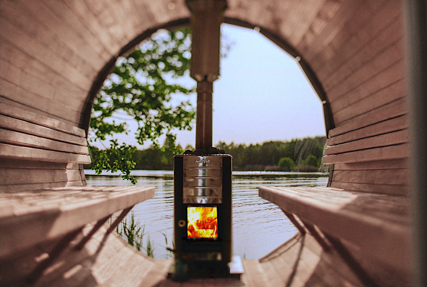 Oryginalna sauna nad wodą z piecem Harvia, widok z wnętrza sauny w Nowym Targu. Drewniane ławki i piec tworzą unikalny klimat relaksu na łonie natury.