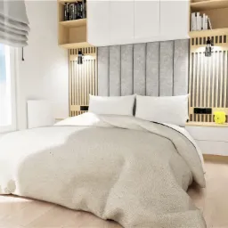 Jasna sypialnia z łóżkiem typu king-size, szarą tapicerowaną ścianą za wezgłowiem, drewnianymi panelami bocznymi z lampkami nocnymi, półkami z książkami i białymi szafkami wiszącymi.