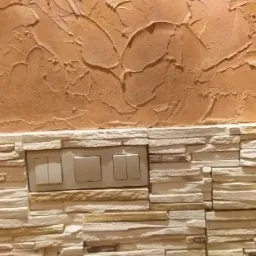 Dekoracyjna ściana z efektem trawertynu i kamienną okładziną z wbudowanymi włącznikami światła.