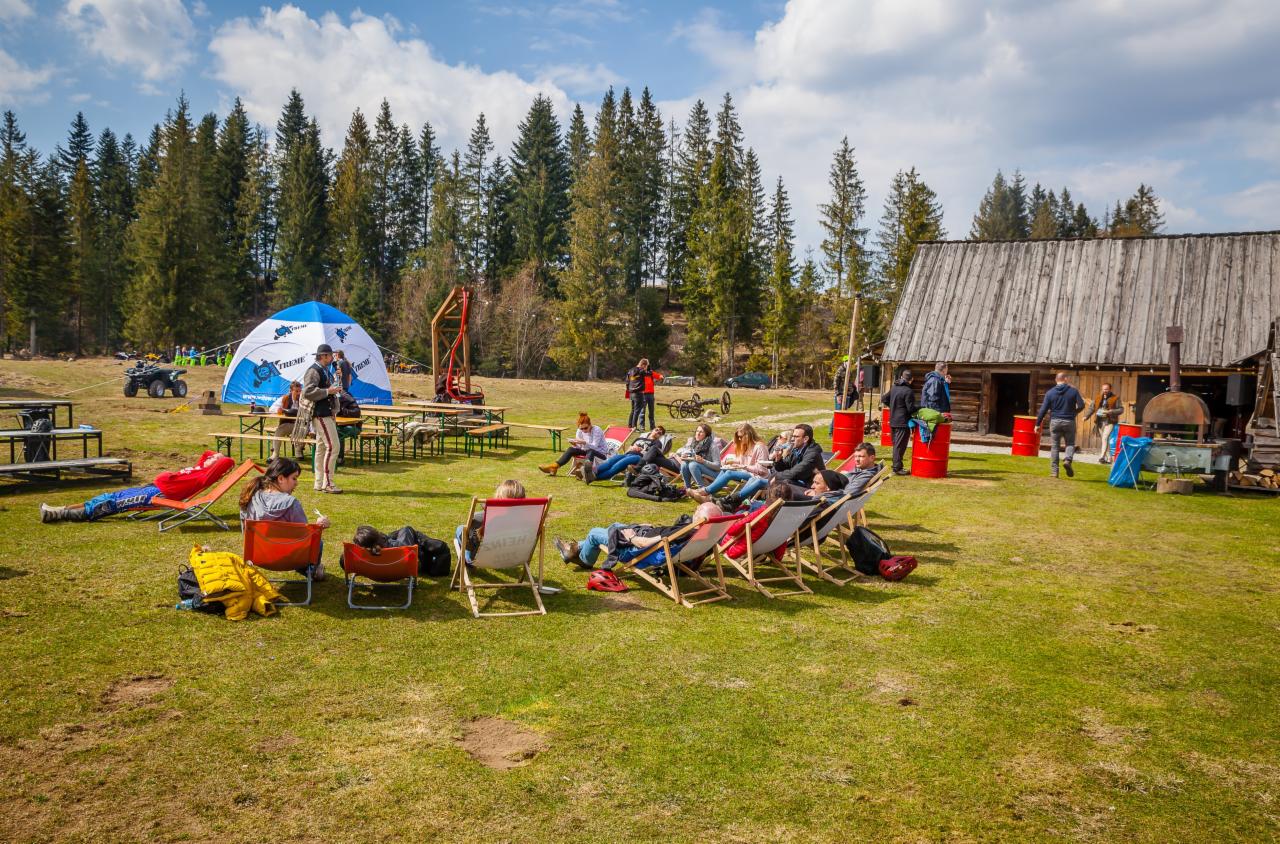 Plenerowa impreza firmowa: relaks gości w leżakach na trawie, w tle drewniana chata, namiot i quady.