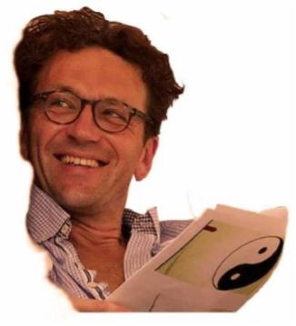 Uśmiechnięty mężczyzna w okularach czyta dokument z symbolem Yin Yang, lekko pochylony w prawo.