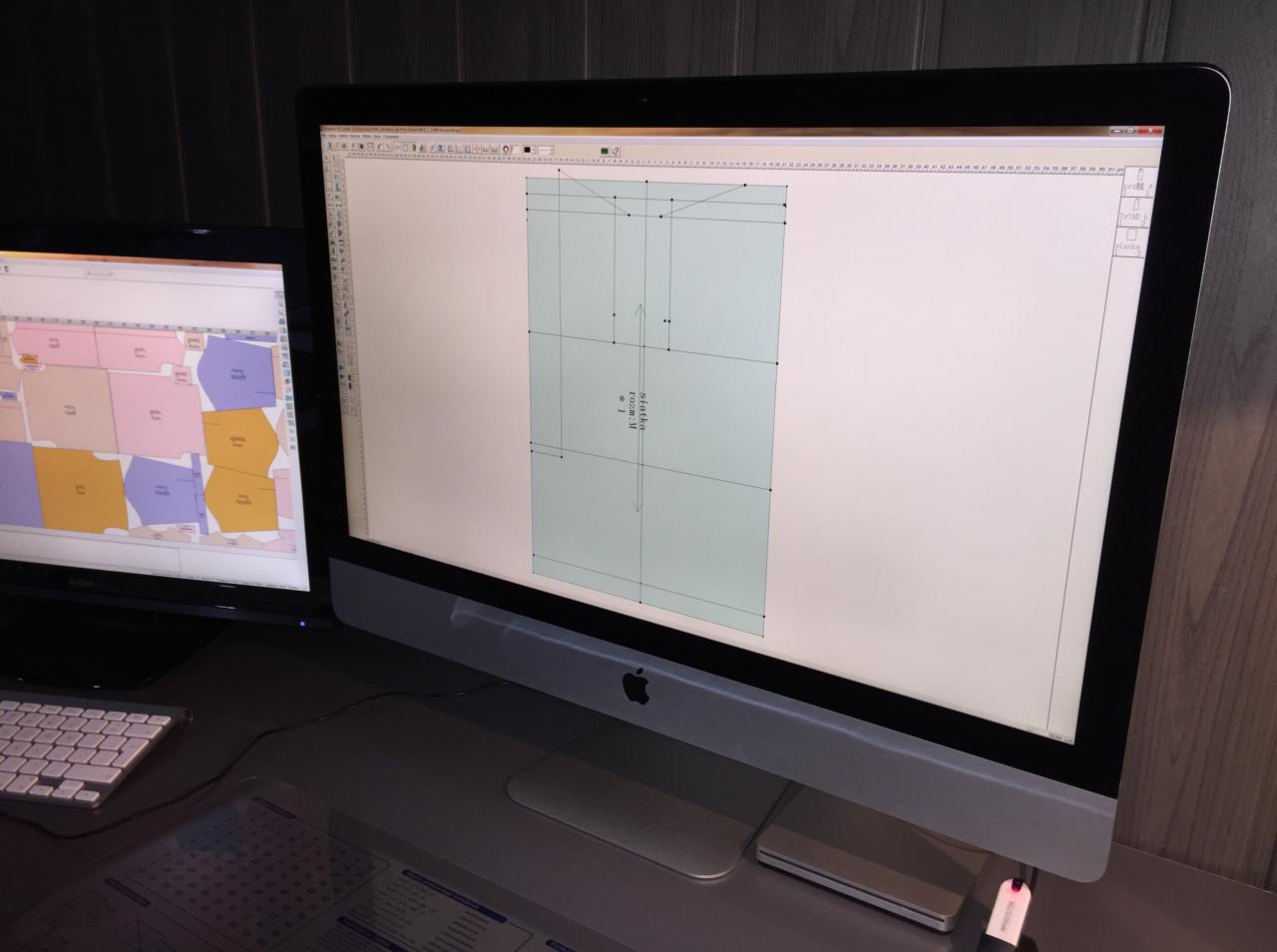 Dwa monitory: na pierwszym widoczny szablon odzieży w programie CAD, na drugim rozkład wykrojów na materiale.