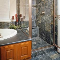 Art.rem USŁUGI REMONTOWO WYKOŃCZENIOWE - Luksusowa łazienka z kabiną prysznicową wyłożoną ciemną, wzorzystą glazurą, drewnianą zabudową wanny i dekoracyjnymi świecami.