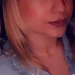 Portret kobiety z blond pasemkami, ubrana w dżinsową koszulę w białe kropki, patrząca w obiektyw.