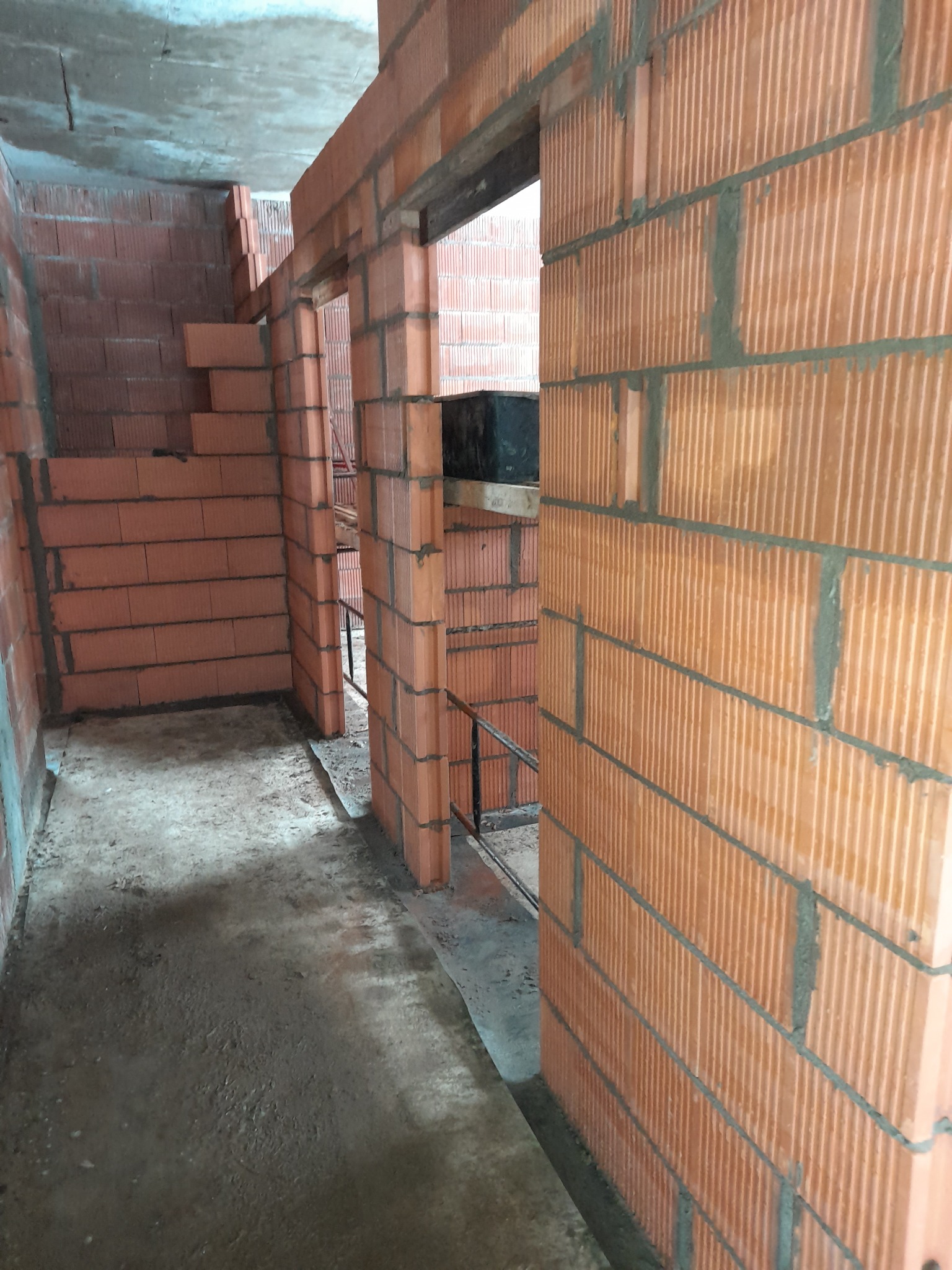 Wnętrze w trakcie budowy z cegły ceramicznej porotherm, widoczne surowe ściany i otwory drzwiowe.