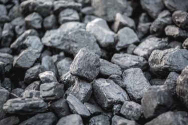 Góra brył antracytu o nieregularnych kształtach, oświetlona naturalnym światłem, z widoczną teksturą i drobnymi pęknięciami na powierzchni.