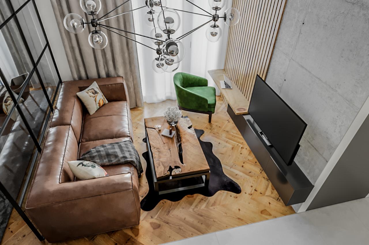 Wnętrze salonu z drewnianą podłogą w jodełkę, skórzaną sofą, zielonym fotelem i stolikiem kawowym z surowego drewna, oświetlone nowoczesną lampą wiszącą z kulistymi kloszami.