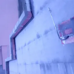 Fragment ściany z nałożoną warstwą gładzi, widoczne ślady po szpachlowaniu i narzędzie w rogu, na ścianie widoczne poziome linie.