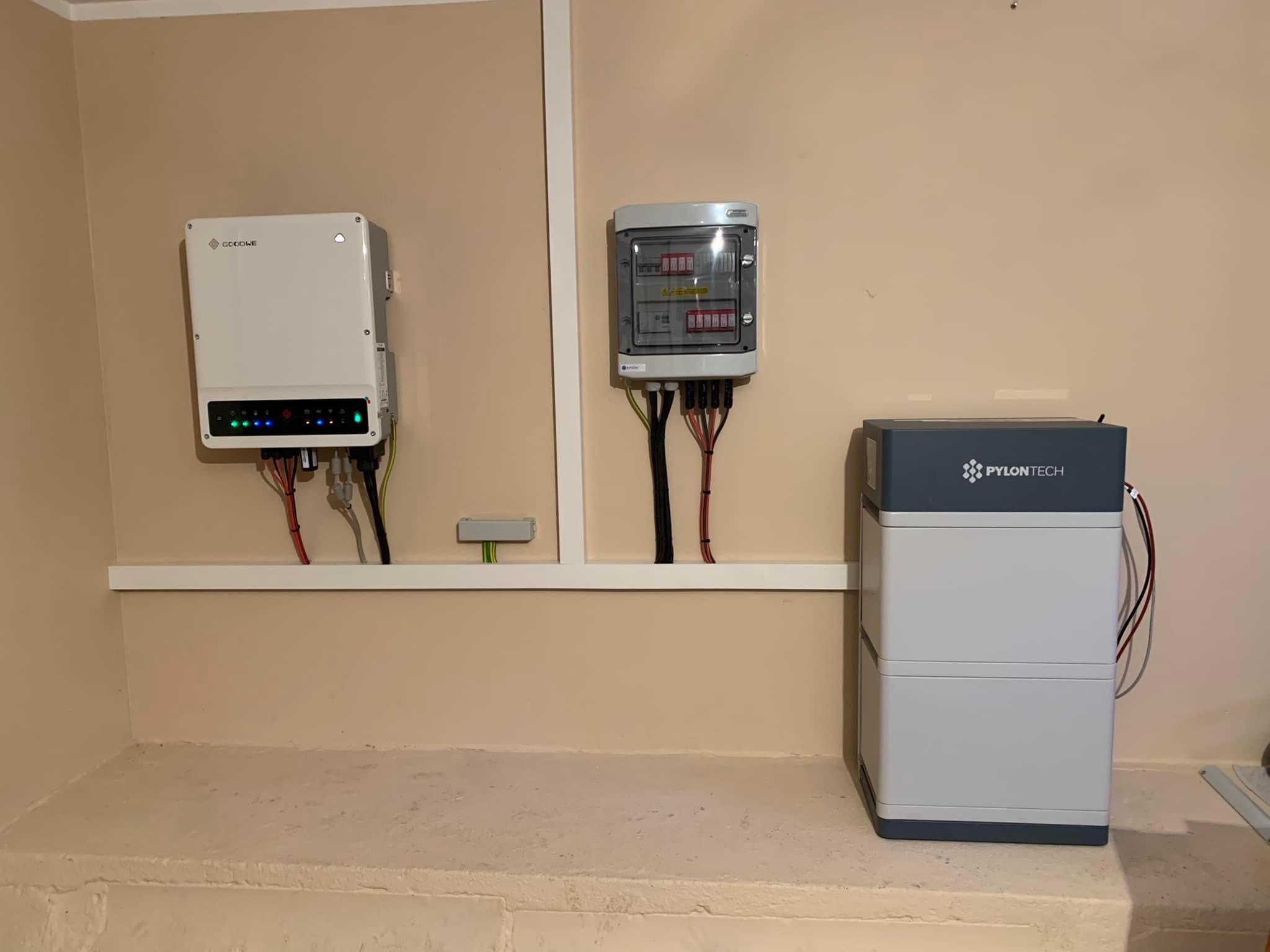 Zestaw fotowoltaiczny w pomieszczeniu: inwerter GoodWe, rozdzielnica elektryczna i magazyn energii Pylontech. Widoczne kable i przewody.