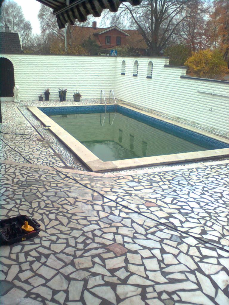 Basen z mozaikową kostką w Bierzwniku, otoczony białym murem z dekoracyjnymi wnękami, widoczny zestaw narzędzi do czyszczenia.