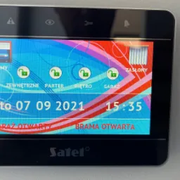 Ekran dotykowy centrali sterującej z interfejsem wskazującym otwartą bramę garażową i wjazdową, data 07.09.2021, godzina 15:35, logo Satel w dolnej części.