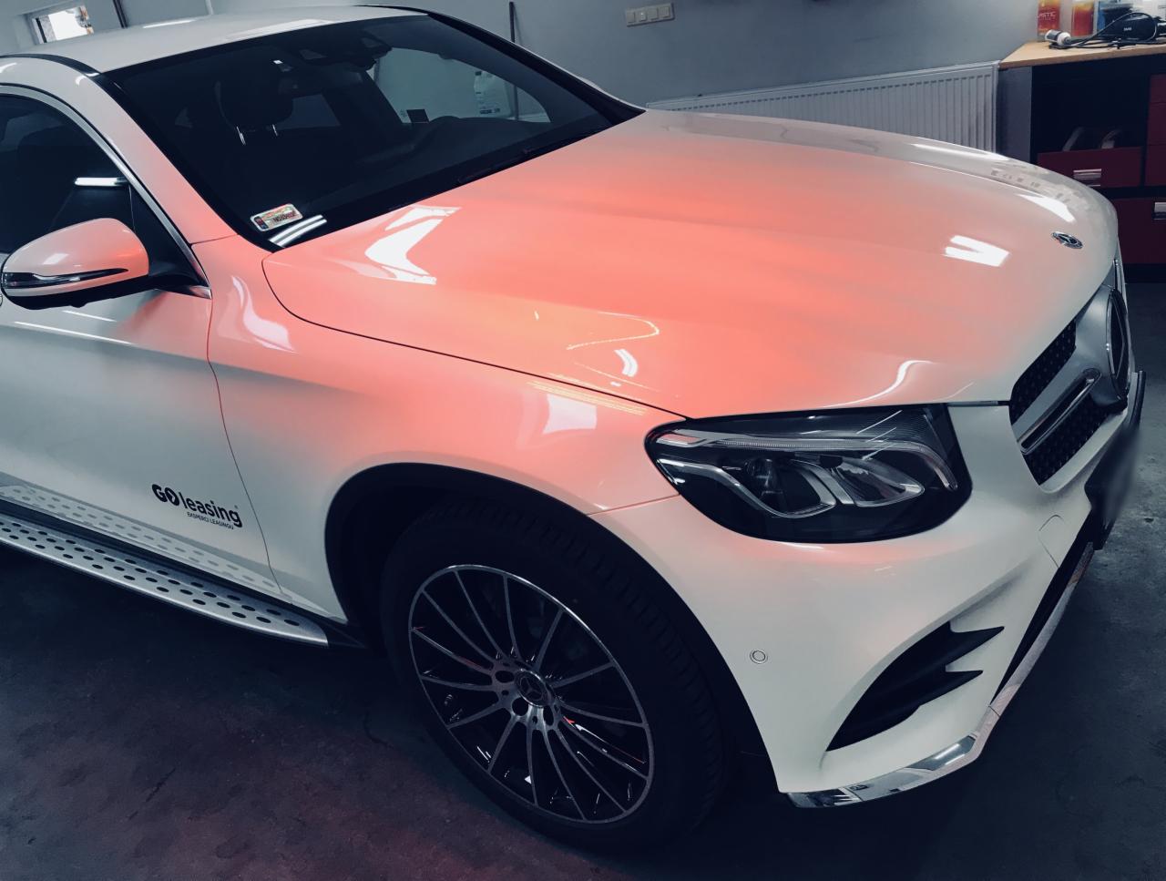 Biały Mercedes GLC po detailingu, z widocznym logo GO Leasing i lśniącą karoserią w ciepłym oświetleniu. Felgi aluminiowe, nowoczesny design.